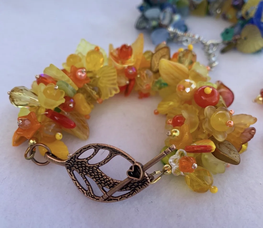 A yellow and orange beaded bracelet with a bronze tree toggle clasp on a white background