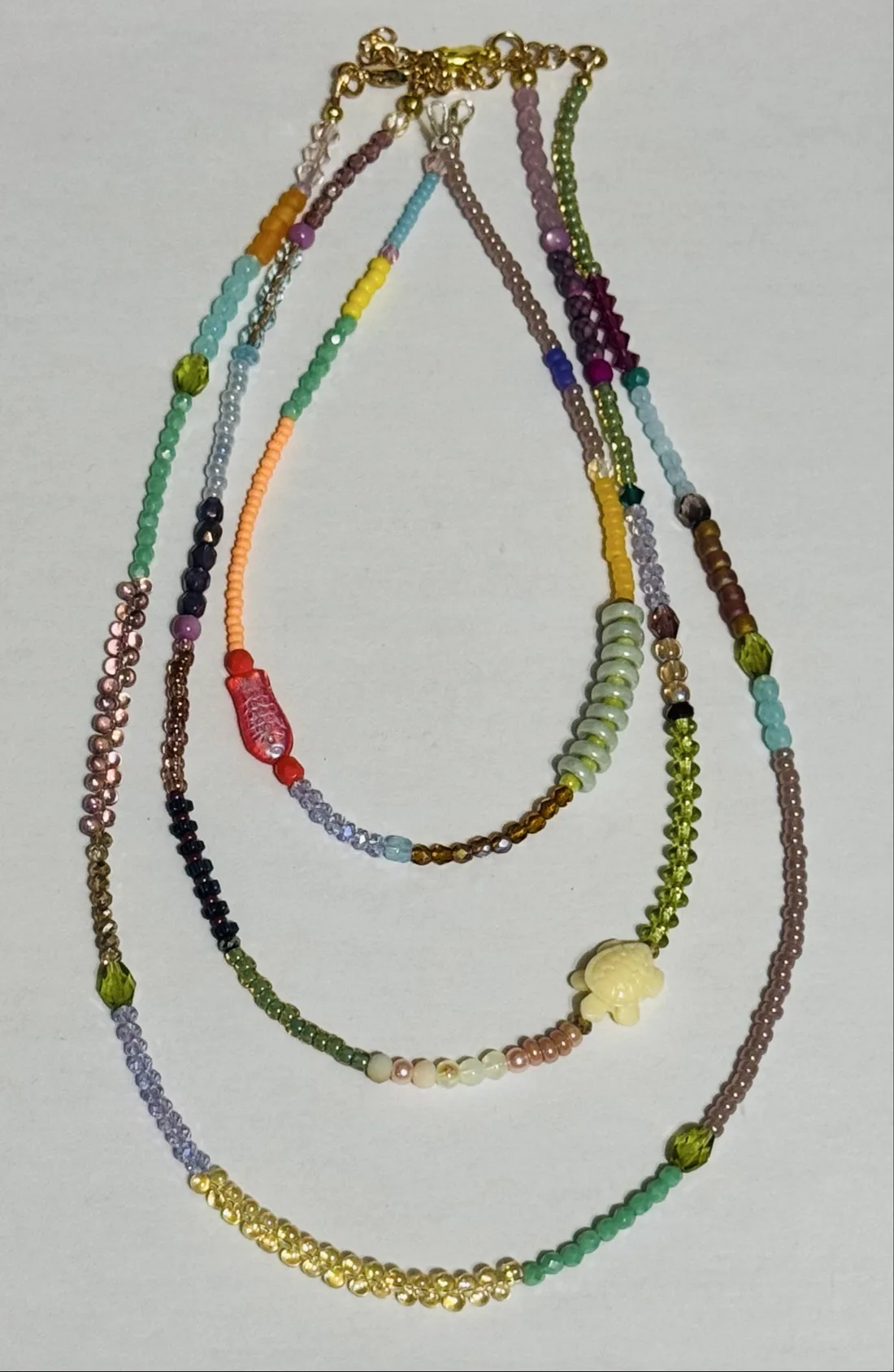 Three delicate beaded seed bead necklaces with charms including a small turtle