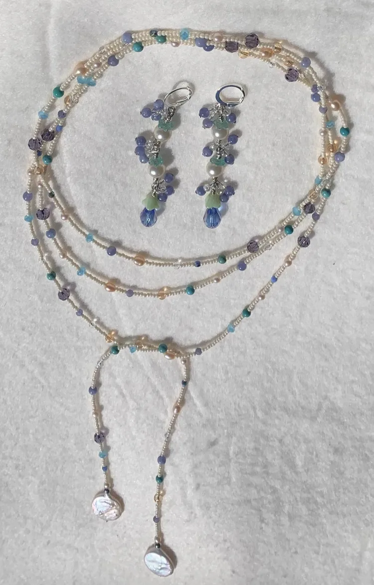 A multi-strand lariat necklace and matching cluster earrings in cream, lavender, and peach