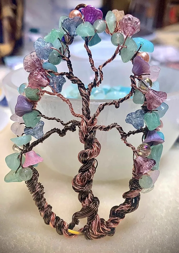 A wire-wrapped tree of life pendant with mint green, blue, and pink stones